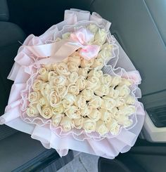 a bouquet of white roses sitting in the back seat of a car with pink ribbon