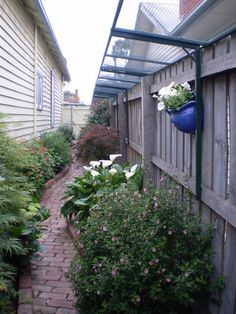 an image of a garden with flowers and plants growing on the side of the house