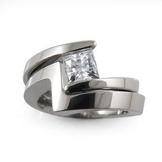 a white gold ring with a princess cut diamond in the center and two bands around it