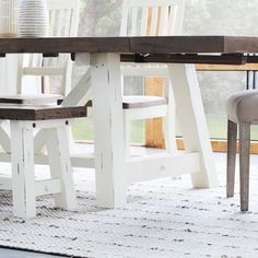 a dining table with two chairs and a bench in front of it on a rug