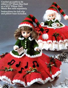 two dolls dressed in red and green dresses with musical notes on the skirt, one wearing a santa claus hat