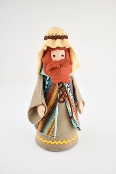 a small doll with a red beard wearing a brown coat and scarf on it's head