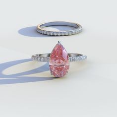 two engagement rings with a pink diamond in the center and white diamonds around them on a light background