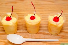 three desserts in plastic cups with cherries on the top and one has a spoon