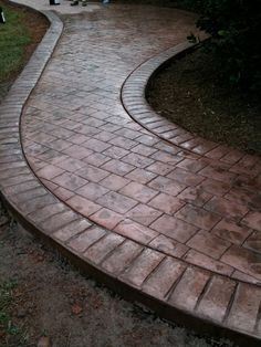 a brick walkway in the middle of a yard with trees and bushes around it,