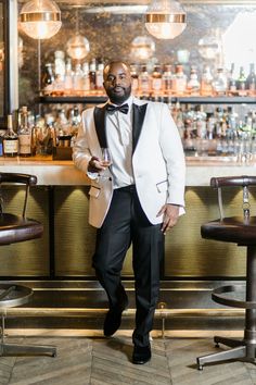 a man in a tuxedo standing next to a bar