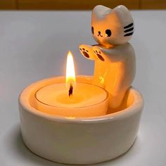 a cat candle holder with a lit candle in it