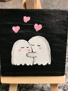 an easel with a painting on it that has hearts coming out of the face