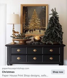 a christmas tree is sitting on top of a dresser in front of a framed painting