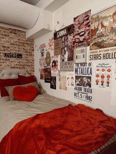 a bed in a bedroom with posters on the wall above it and a red blanket