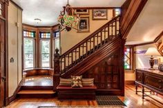 an entryway with wooden stairs and wood flooring is pictured in this house's foyer