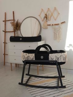 a black and white baby crib sitting on top of a rug next to a dresser