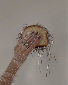 a woman's hand holding up a piece of bread with nails on top of it