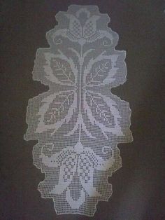 a white doily on a black surface with an intricate design in the center and bottom