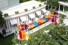 an aerial view of a multicolored building with trees in the foreground and lawn