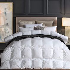 a white comforter on a bed in a room with two lamps and pictures above it