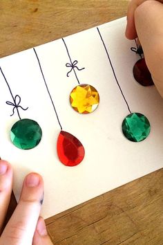 someone is making christmas ornaments out of paper and stringing them with colored glass beads