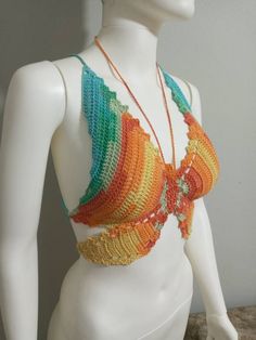 a white mannequin wearing a multicolored crochet top and necklace