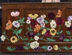 a wooden bench with flowers painted on the back and sides, in front of an audience