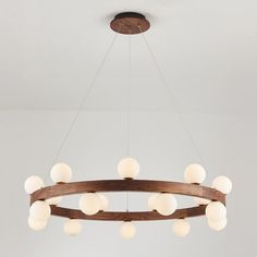 a wooden circular light fixture with white glass balls hanging from it's center circle