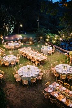 an outdoor dining area with tables, chairs and umbrellas lit up by string lights