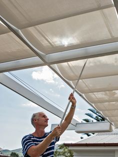 an older man is fixing the awnings on his home's patio area