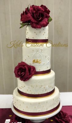 a three tiered wedding cake with red roses on top and gold trimmings