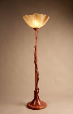 a wooden floor lamp with a glass shade on it's top and an iron base