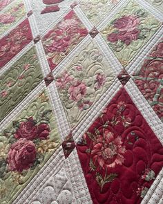 a quilted table topper with red and green flowers on it's edges