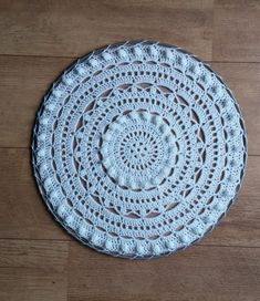 a white crocheted doily sitting on top of a wooden floor