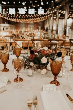 the table is set with gold wine goblets and place settings for dinner guests