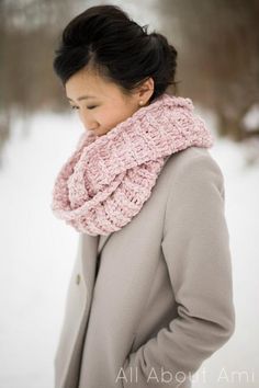 a woman standing in the snow wearing a pink scarf