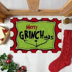 a christmas door mat with the words merry grinmas on it next to stockings and presents