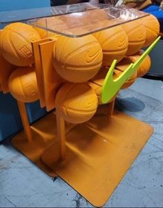 there is a table made out of orange balls and plastic cups on the floor with yellow handles