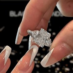 a woman's manicured nails are adorned with a diamond ring and white acrylic