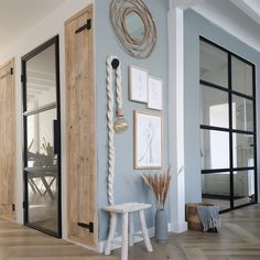 a room with blue walls and pictures on the wall next to a white stool in front of a wooden door