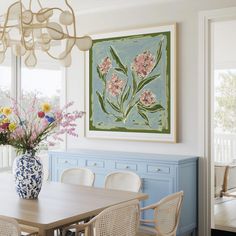 a vase with flowers is sitting on a table in front of a blue and white cabinet