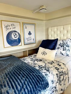 a bed with blue and white comforter in a bedroom next to two pictures on the wall