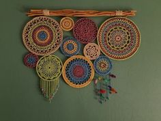 a wall hanging made out of different colored doily and wood sticks with beads on it