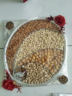 three metal trays filled with nuts on top of a white countertop next to red flowers