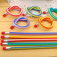 several different colored pencils sitting next to each other on top of a wooden table