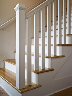 a white staircase with wooden handrails and wood flooring