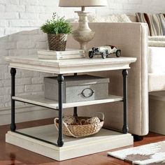 an end table with two drawers and a lamp on top, in front of a couch