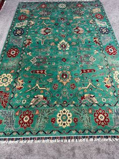 a green rug with red, white and blue designs on the middle is laying on carpet