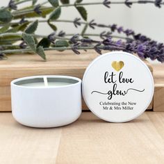 a white candle sitting on top of a wooden table next to a potted plant