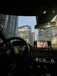 the interior of a car with city buildings in the background at night time, as seen from driver's point of view