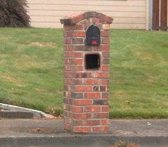 a brick mailbox sitting on the side of a road in front of a house