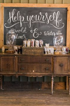 an old dresser with jars and glasses on it in front of a chalkboard that says help yourself