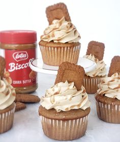 cupcakes with frosting and cookies on a plate next to a jar of biscuit