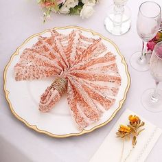 a plate with an umbrella on it next to wine glasses and flowers